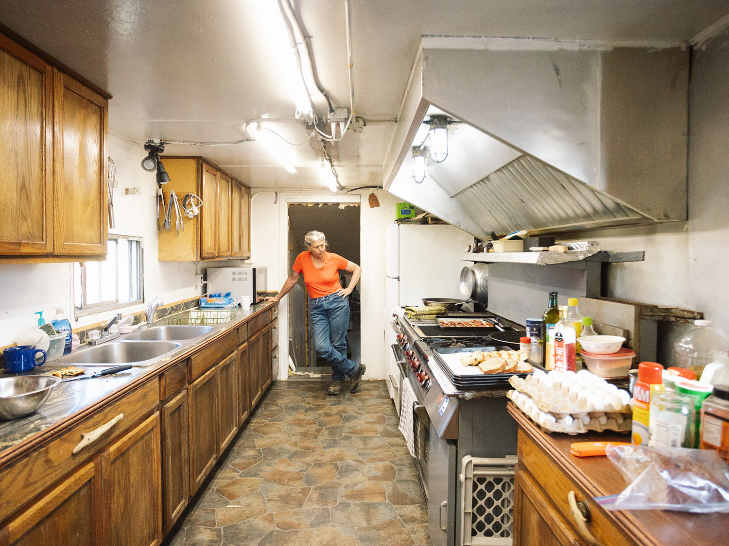 Sue Aikens in the Kavik River Camp Kitchen – Life Below Zero Sue Aikens standing in the Kavik River Camp kitchen on Alaska's North Slope, with eggs, bread, and food cooking on a commercial range